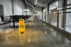 A long balcony hallway stretches beyond a yellow caution sign, slip and fall accident